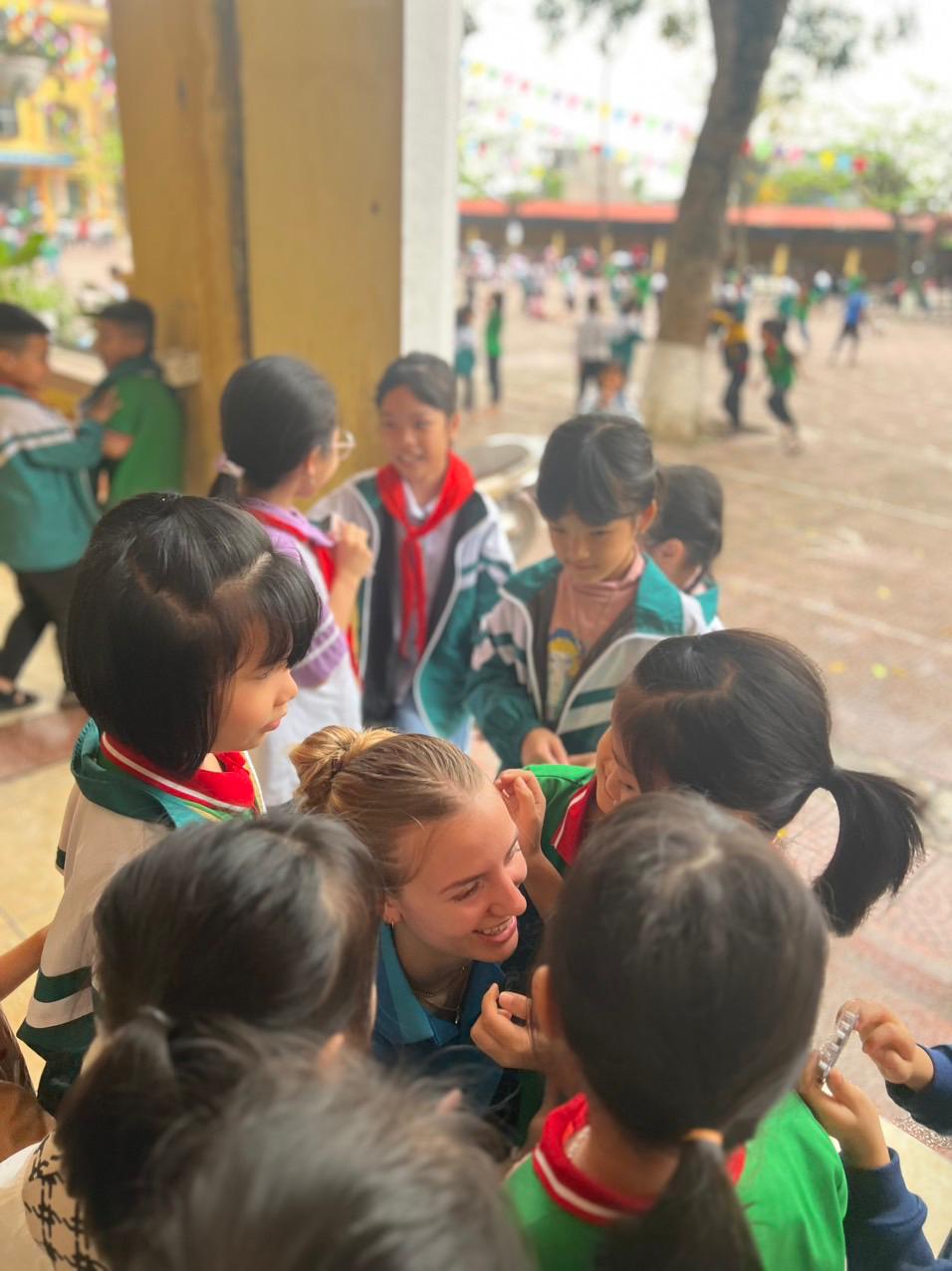 Gotoco'er surrounded by primary school students in a Vietnamese schoolyard